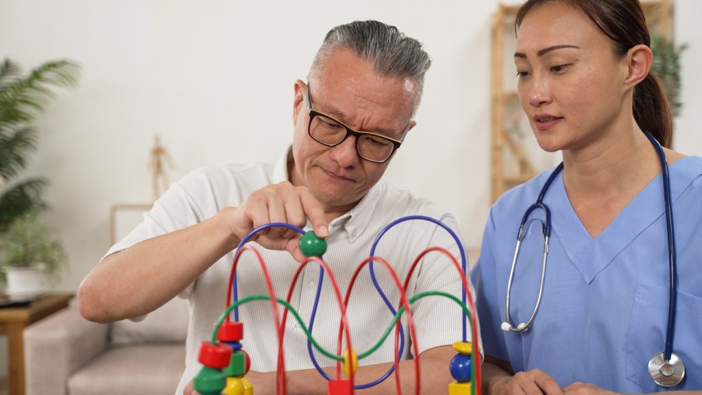 A man in glasses playing with a bead maze toy.